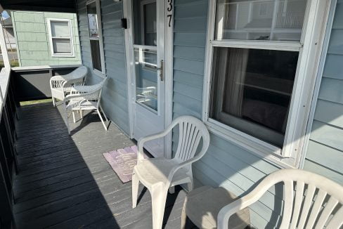 A porch with two chairs and a table.