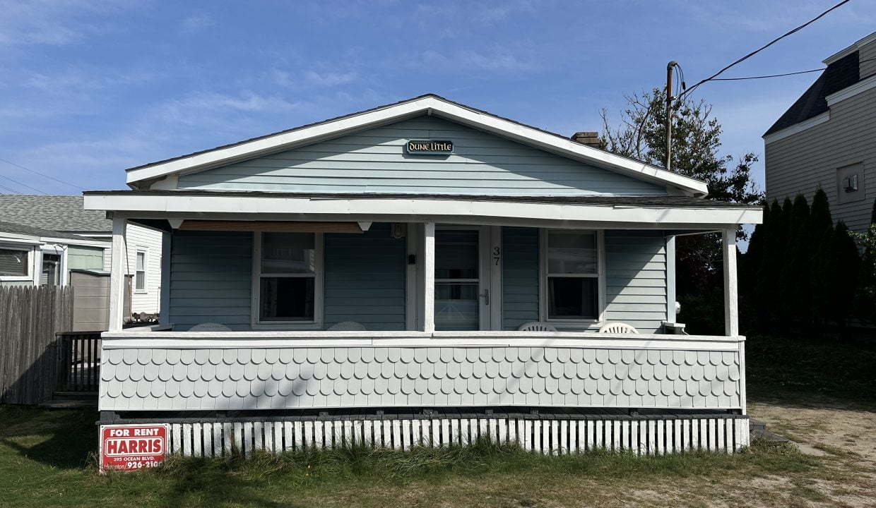 A small blue house with a sign on it.