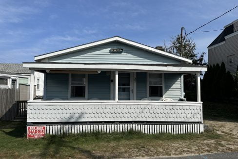 A small blue house with a sign on it.