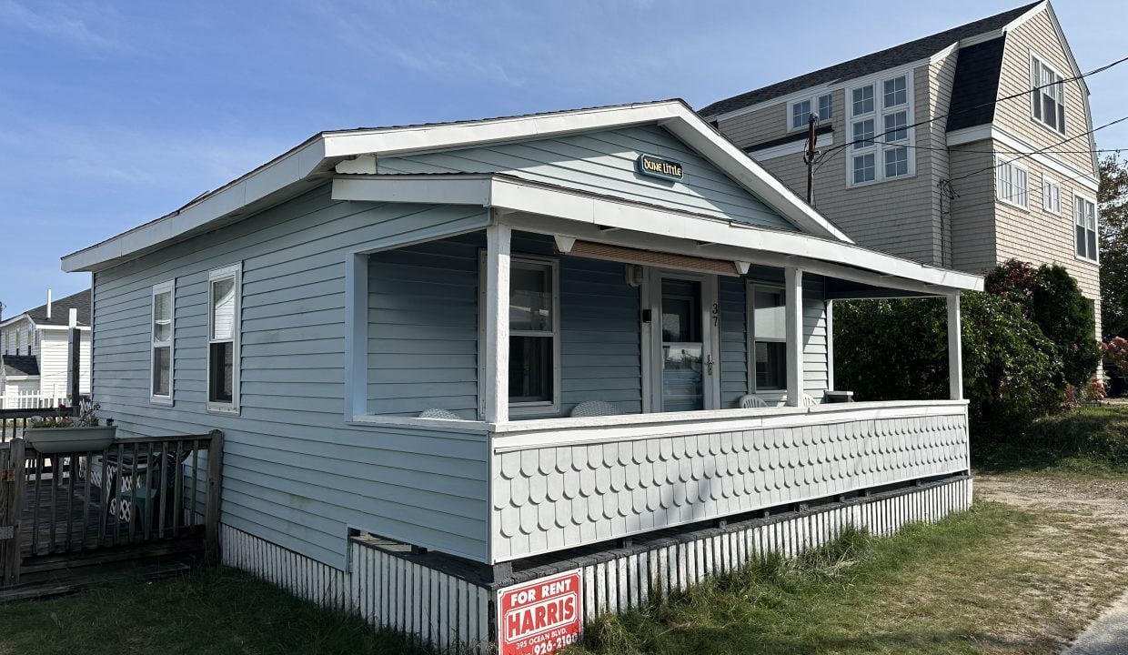 A small blue house with a sign on it.