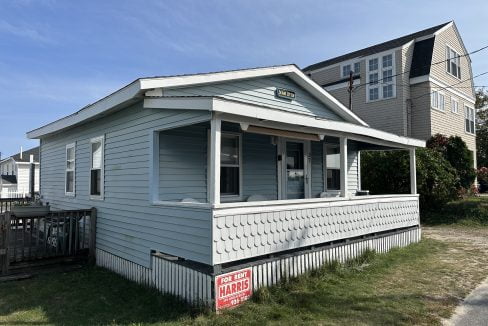 A small blue house with a sign on it.