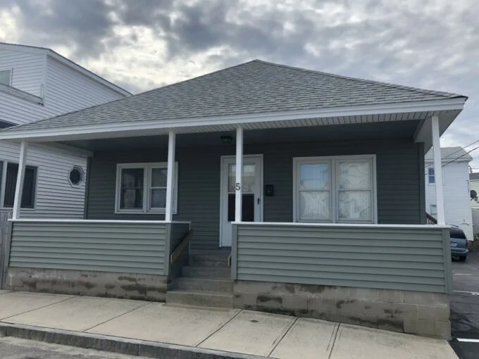 a gray house with white trim and a gray roof.