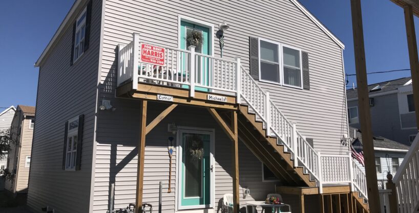 a white house with a green door and a balcony.