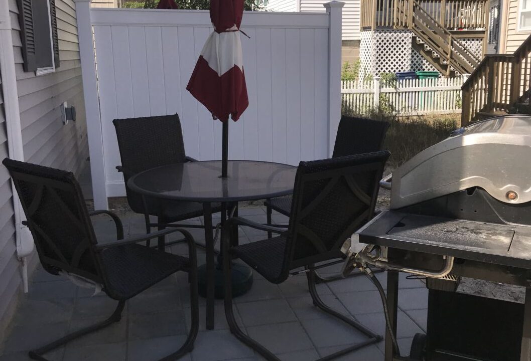 a patio with a table and chairs and a grill.