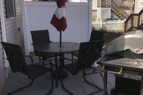 a patio with a table and chairs and a grill.