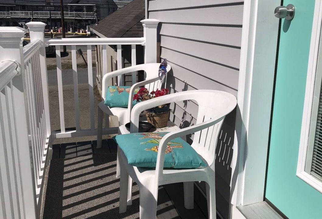 a couple of white chairs sitting on top of a porch.