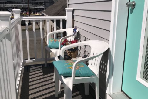 a couple of white chairs sitting on top of a porch.