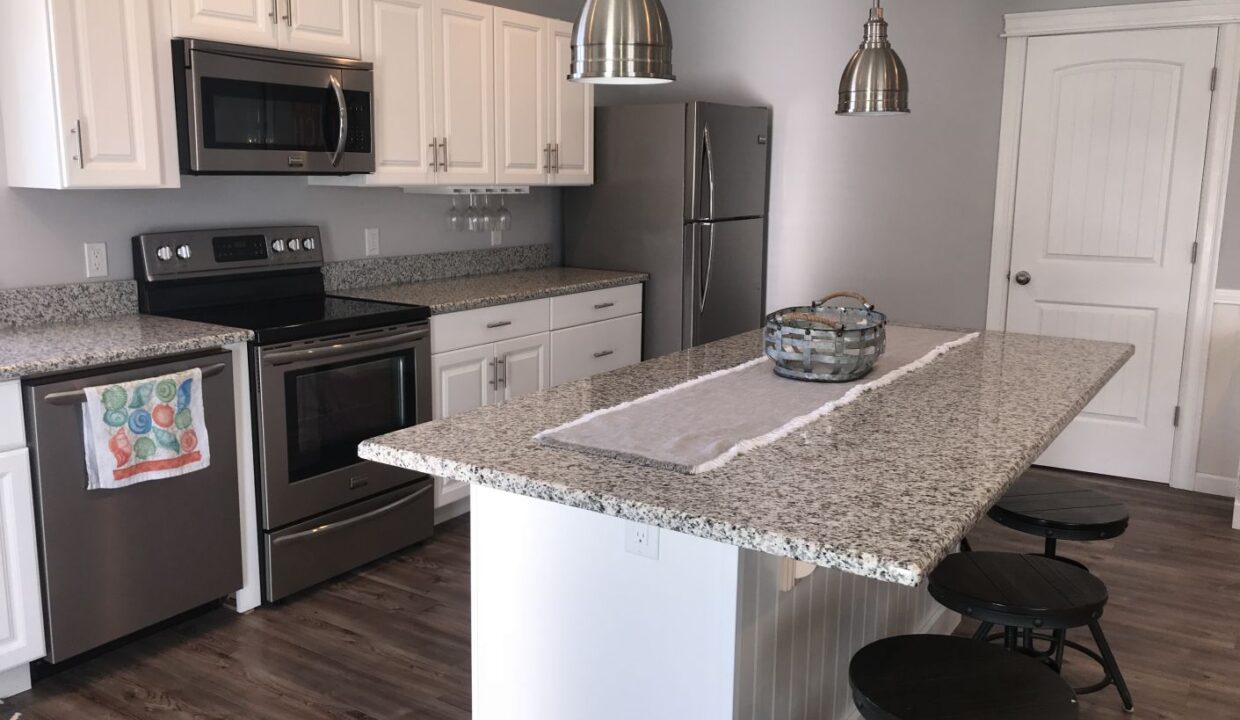 a kitchen with an island, stove, microwave, and dishwasher.