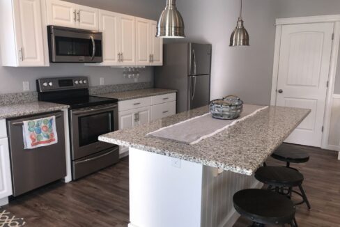 a kitchen with an island, stove, microwave, and dishwasher.