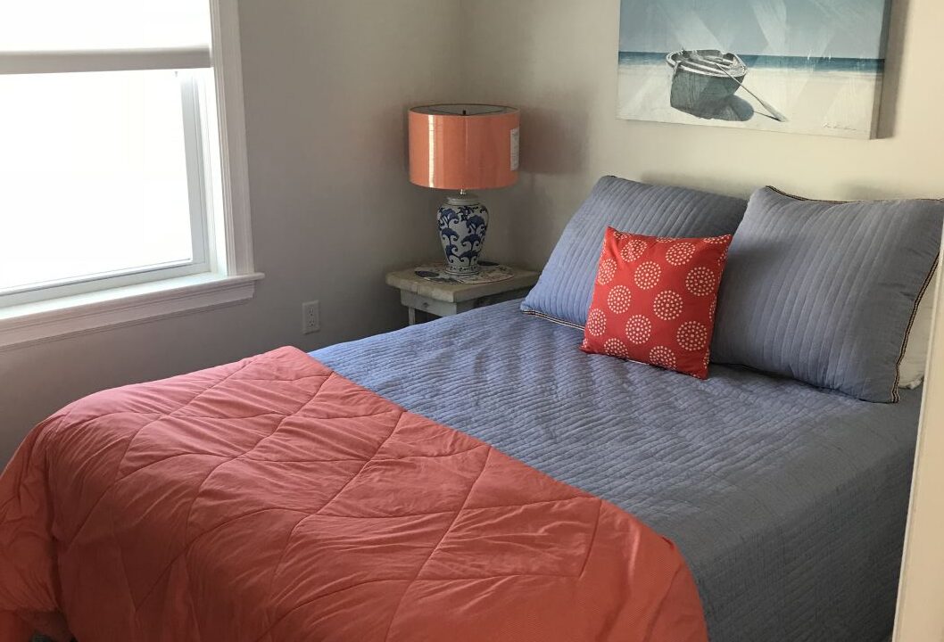 a bed with a blue and orange comforter in a bedroom.
