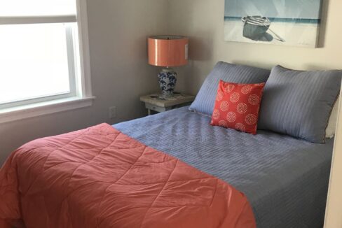 a bed with a blue and orange comforter in a bedroom.