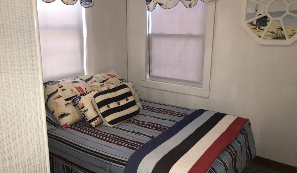 a bed sitting in a bedroom next to two windows.