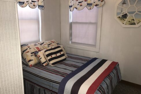 a bed sitting in a bedroom next to two windows.