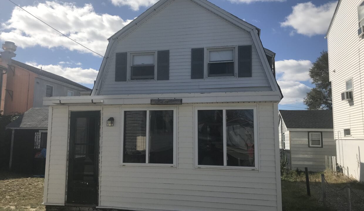 a small white house sitting in the middle of a yard.