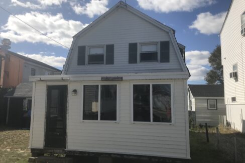 a small white house sitting in the middle of a yard.