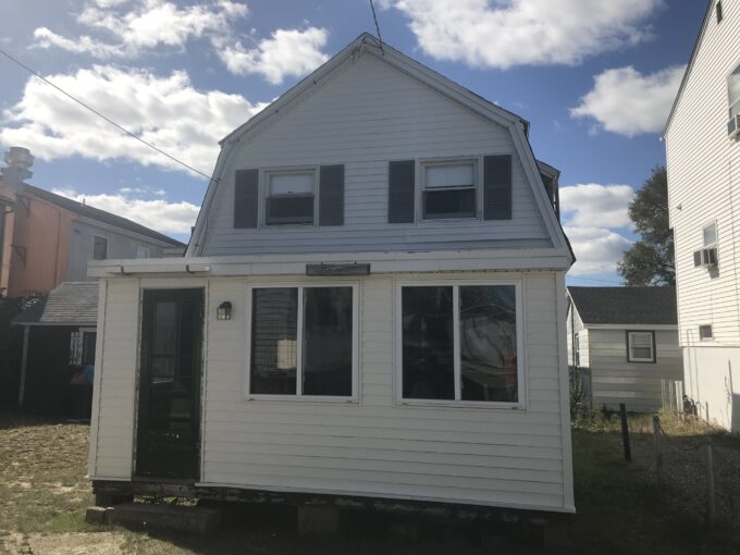 a small white house sitting in the middle of a yard.