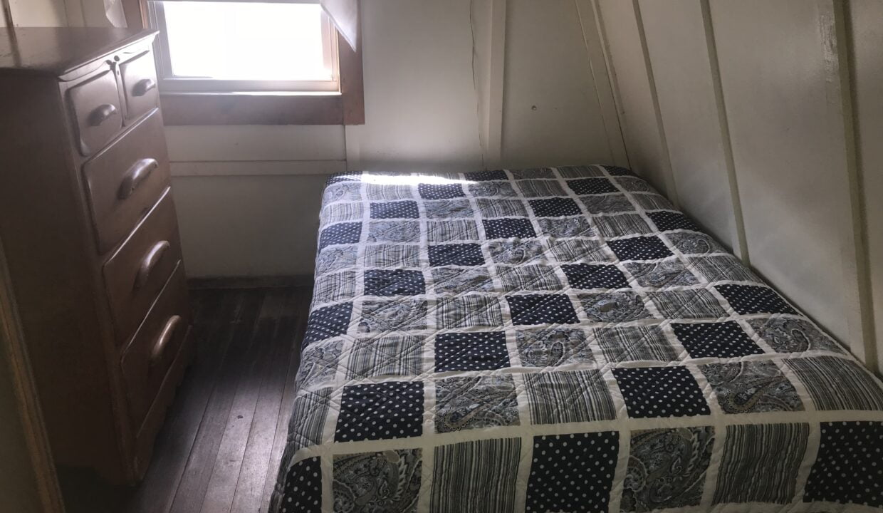 a bedroom with a bed, dresser and window.