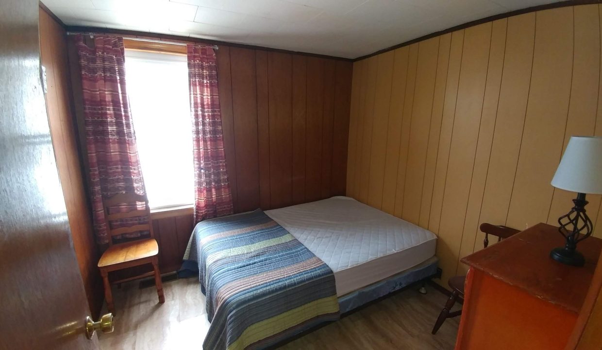 a bedroom with wood paneling and a bed.