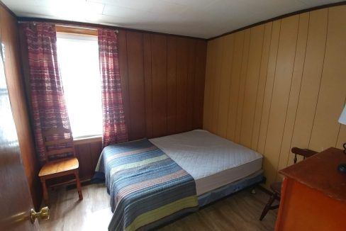 a bedroom with wood paneling and a bed.