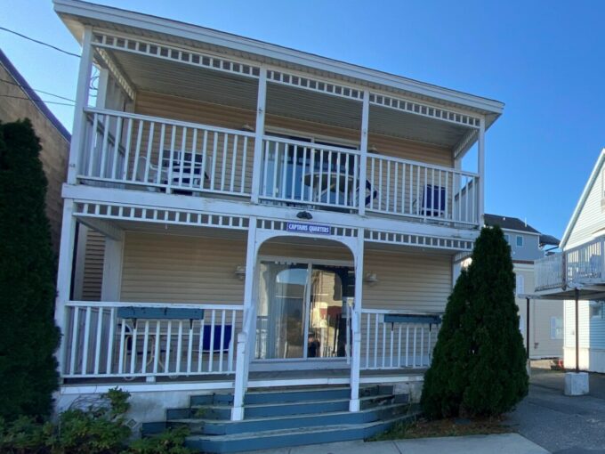 a two story white building with balconies on the second floor.