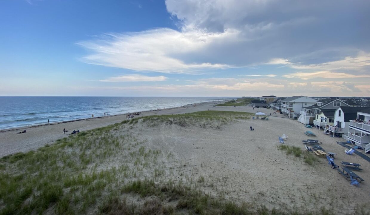 a sandy beach next to the ocean under a cloudy sky.