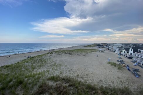 a sandy beach next to the ocean under a cloudy sky.