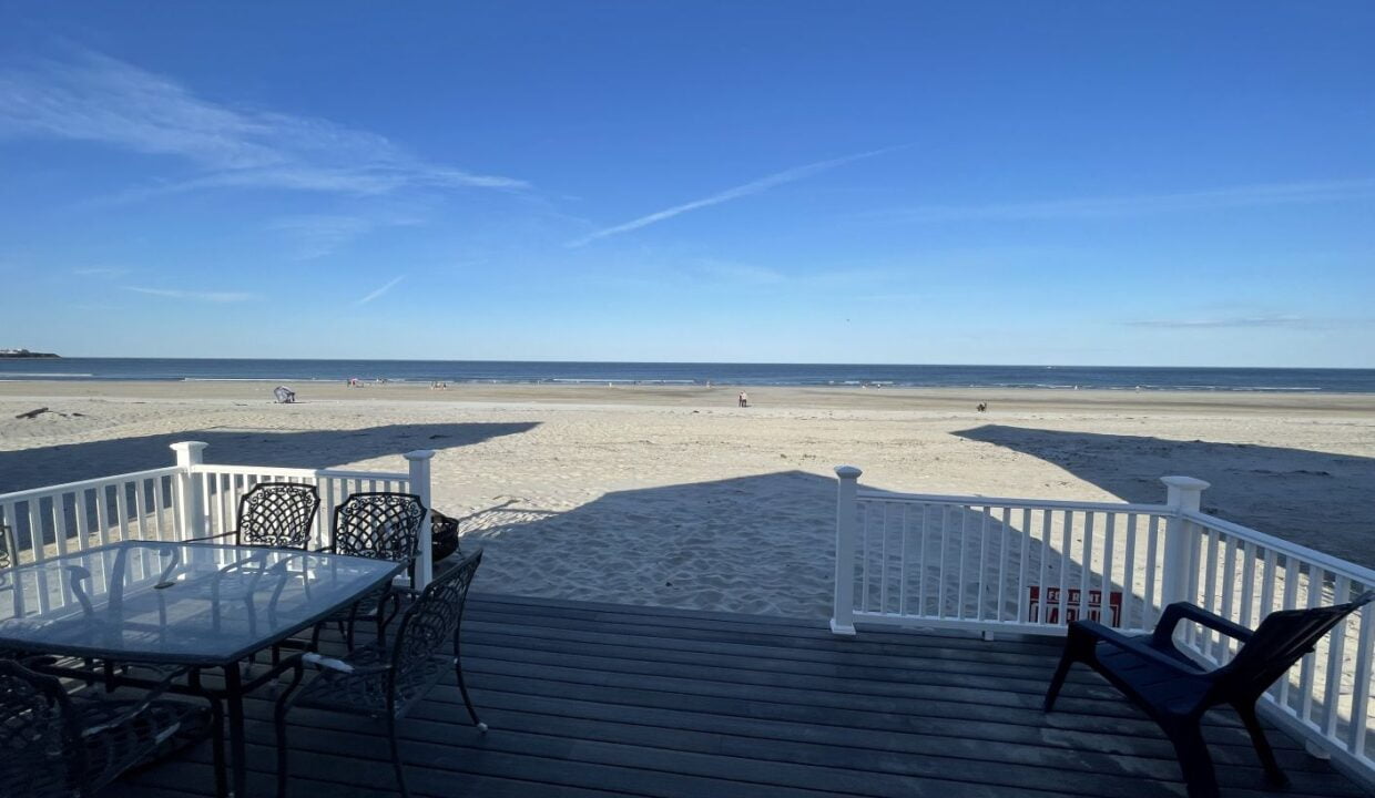 a table and chairs on a deck overlooking the beach.