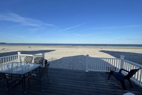 a table and chairs on a deck overlooking the beach.