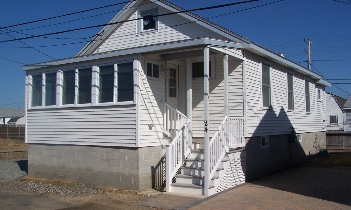 a small white house with a porch and stairs.