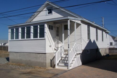 a small white house with a porch and stairs.