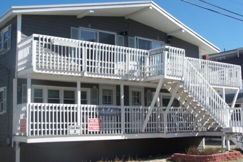a two story house with white balconies and white railings.
