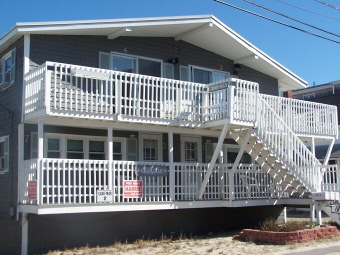 a two story house with white balconies and white railings.