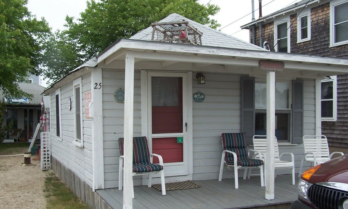 a small house with two chairs on the porch.