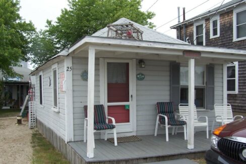 a small house with two chairs on the porch.