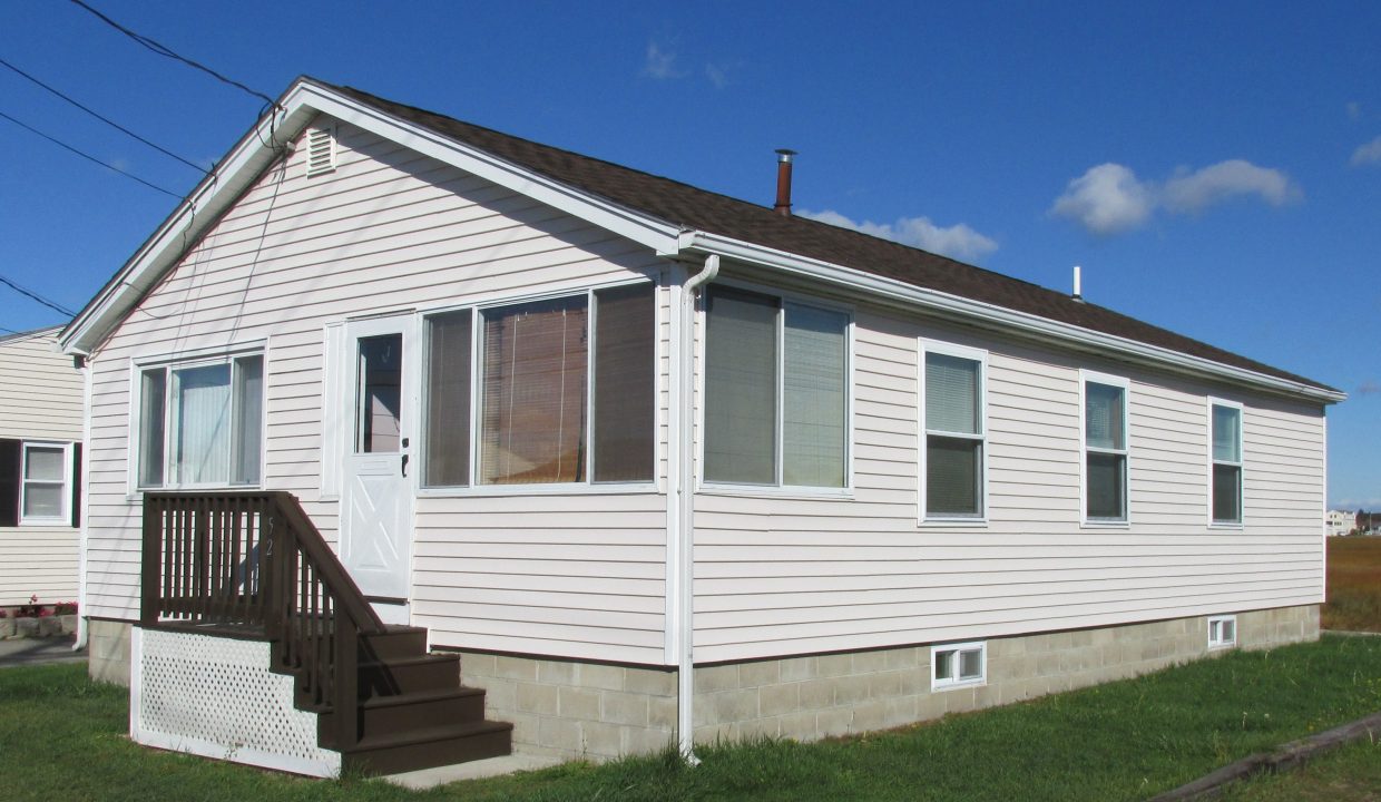 a small white house with a brown porch.