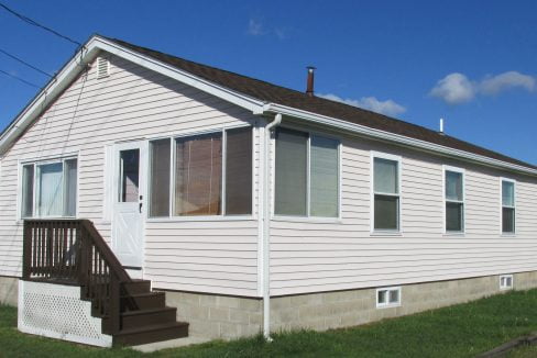 a small white house with a brown porch.