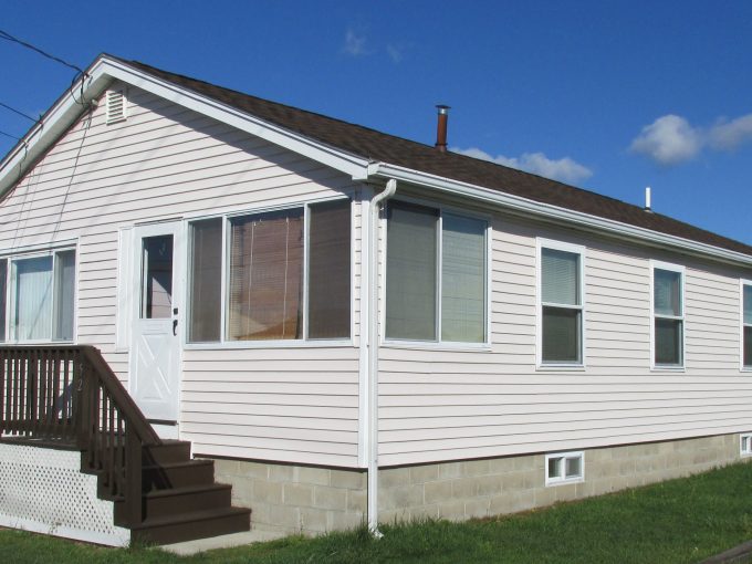 a small white house with a brown porch.