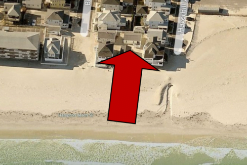 an aerial view of a beach with houses and a red arrow.