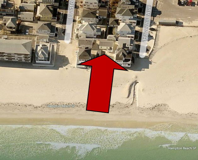 an aerial view of a beach with houses and a red arrow.