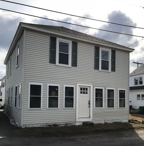 a two story house with a white door and windows.