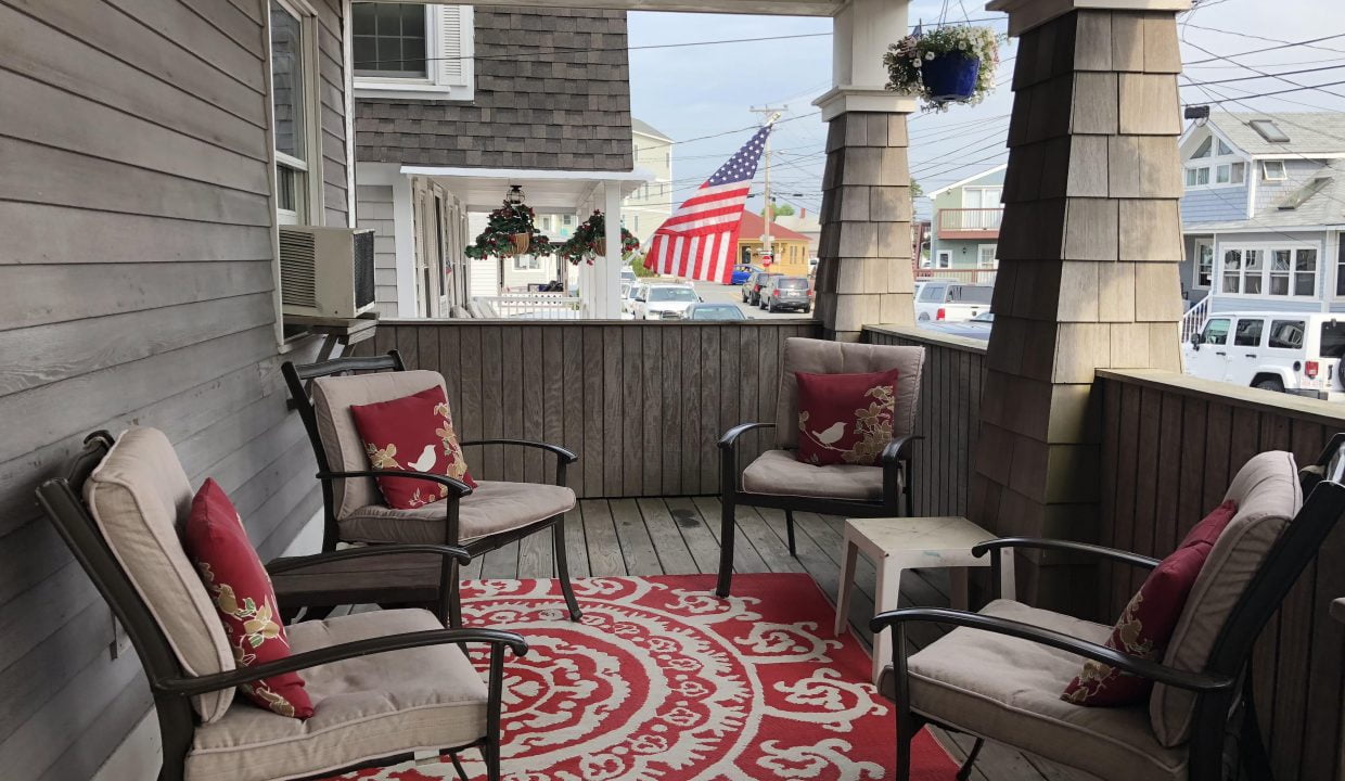 a porch with chairs and a rug on it.