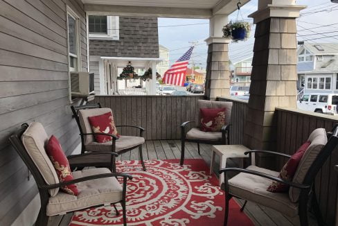 a porch with chairs and a rug on it.