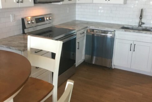 a kitchen with white cabinets and a wooden table.