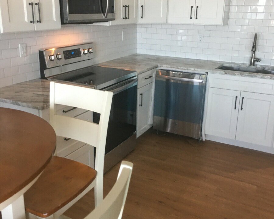 a kitchen with white cabinets and a wooden table.