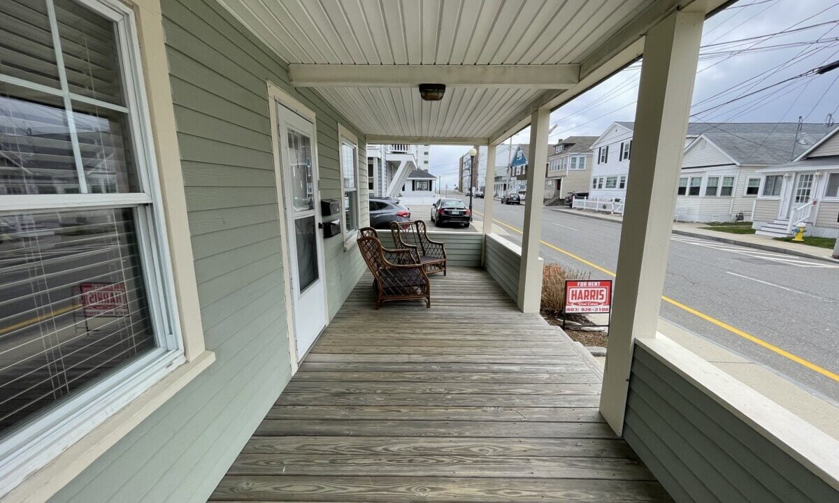 a porch with chairs and a sign on the side of it.