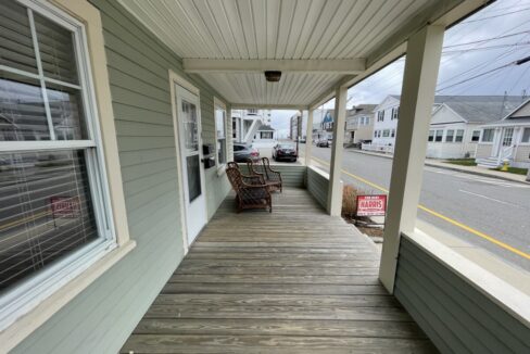 a porch with chairs and a sign on the side of it.