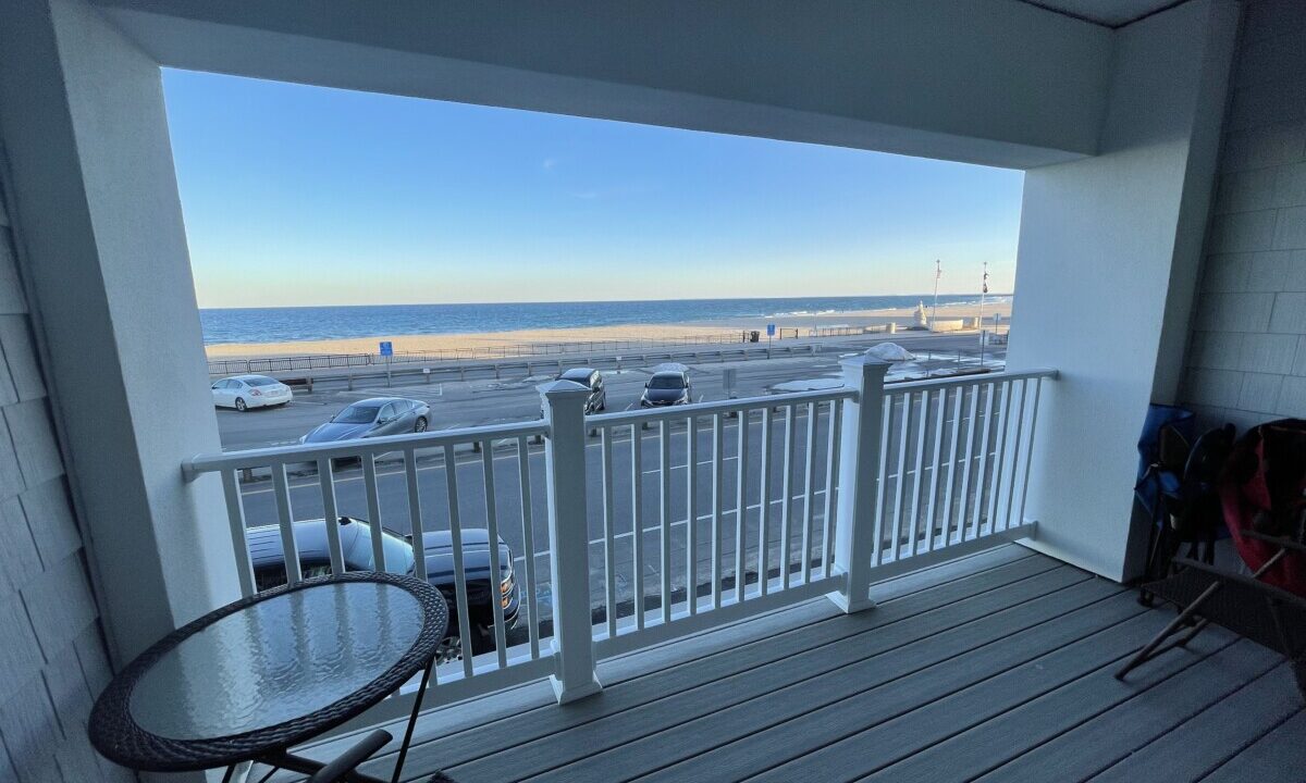 a balcony with a table and chairs and a view of the beach.