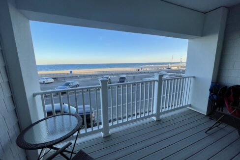 a balcony with a table and chairs and a view of the beach.