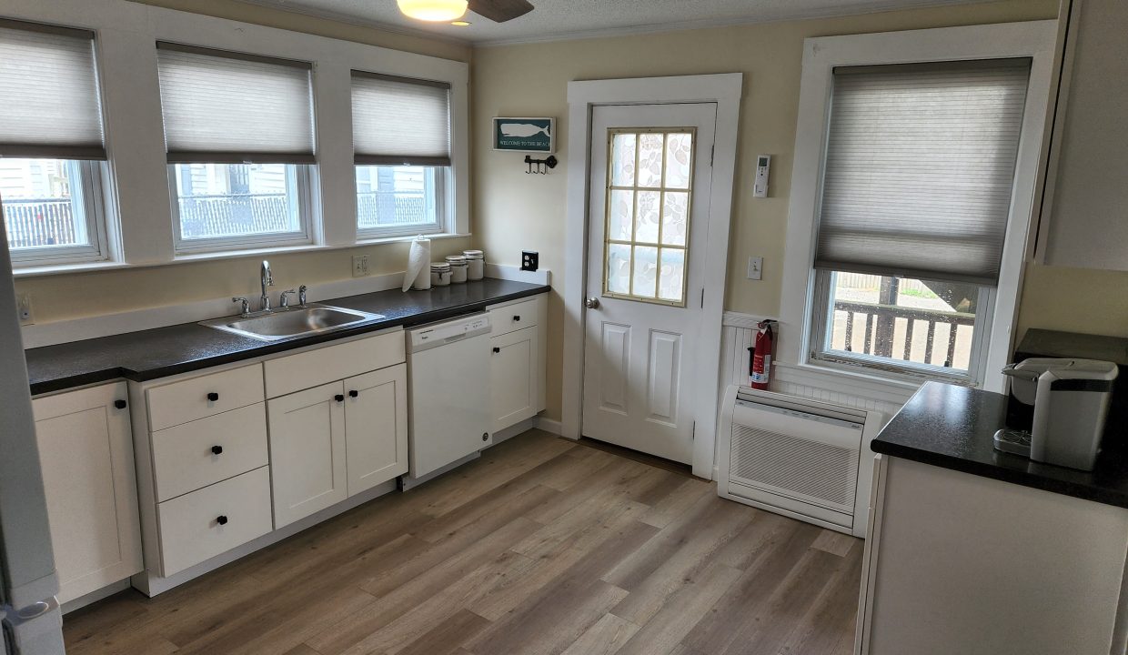 a kitchen with white cabinets and black counter tops.