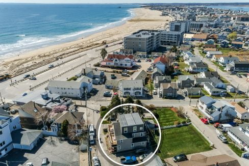 Aerial view of a coastal neighborhood with varied housing, highlighted by a circled house near the beach and roads lined with other residences.